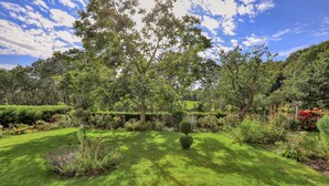 A well-maintained garden with a variety of plants and trees, a neatly trimmed lawn, and a clear sky.