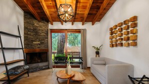 A living room with a fireplace, wooden furniture, a grey sofa, and a wall art piece. - Forest Guesthouse Avándaro, entertainment and comfort for adults and children (Valle de Bravo)