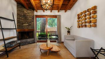 A living room with a fireplace, wooden furniture, a grey sofa, and a wall art piece.