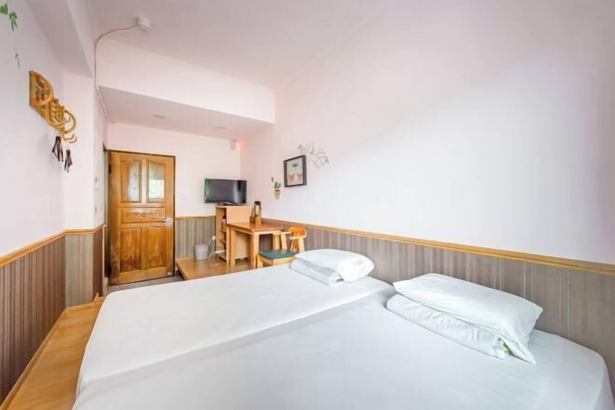 Een hotelkamer met een bed, bureau, stoel, televisie en een deur.