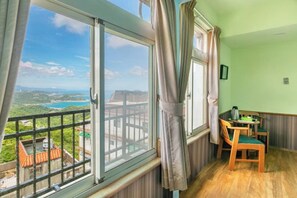 A room with a large window, a balcony, and a small table with chairs. - Kite Museum (New Taipei City)