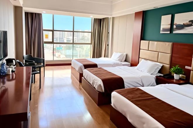 A hotel room with two beds, a desk, and a TV.