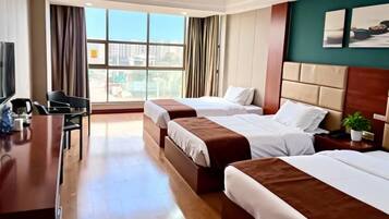 A hotel room with two beds, a desk, and a TV.