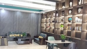 A modern living room with a sofa set, a dining table, and a bookshelf with decorative items. - Pai Hotel (Chenzhou Yizhang County Yiren Plaza Branch) (Yizhang)