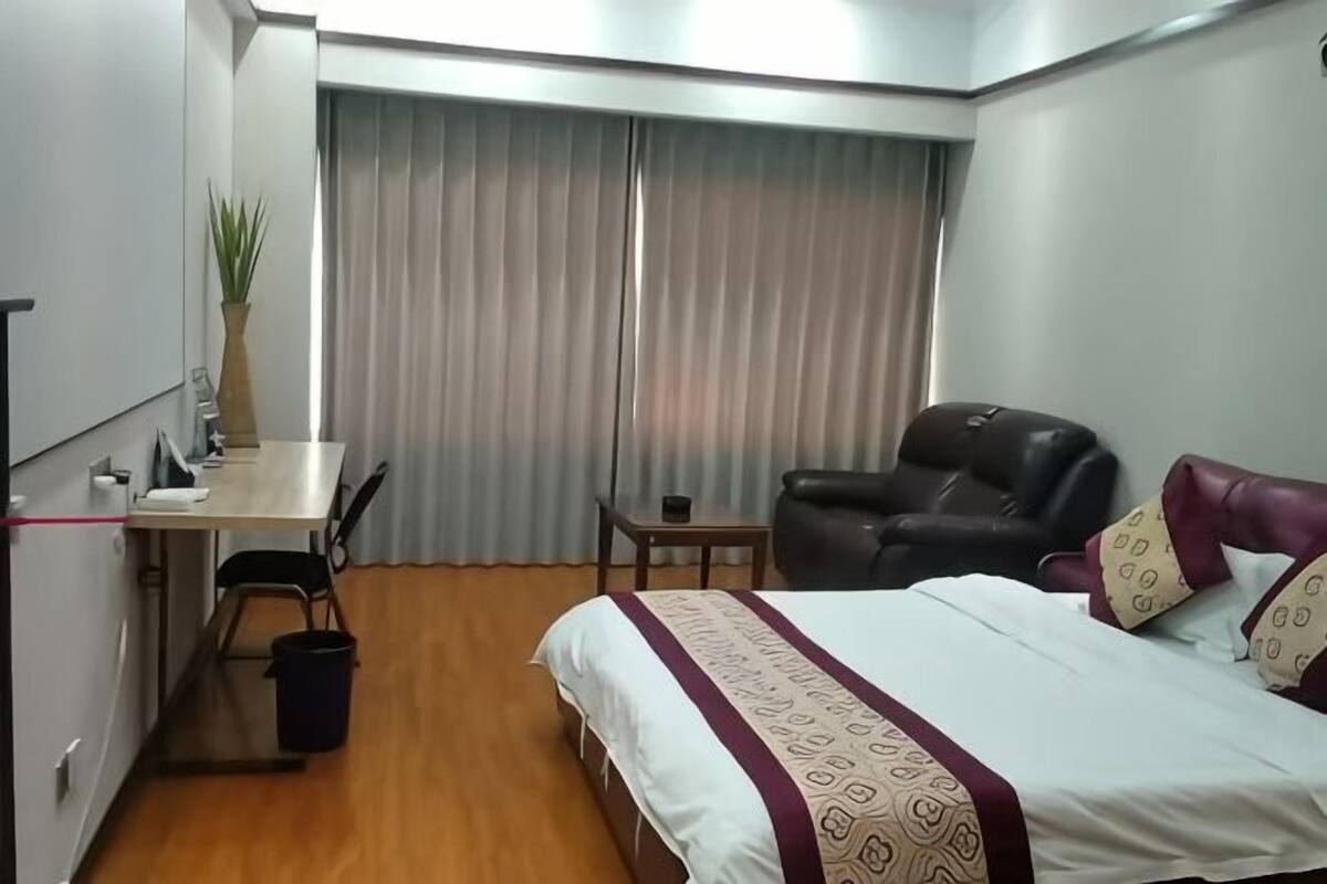 Een hotelkamer met een bed, bureau, stoel en gordijnen.
