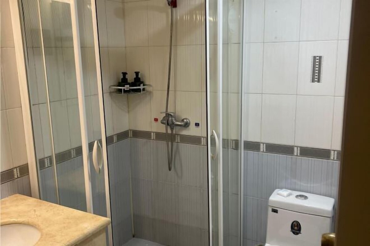 A bathroom with a glass-enclosed shower, a toilet, and a sink.
