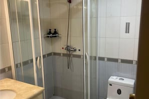 Een badkamer met een douchecabine, toilet en wastafel.