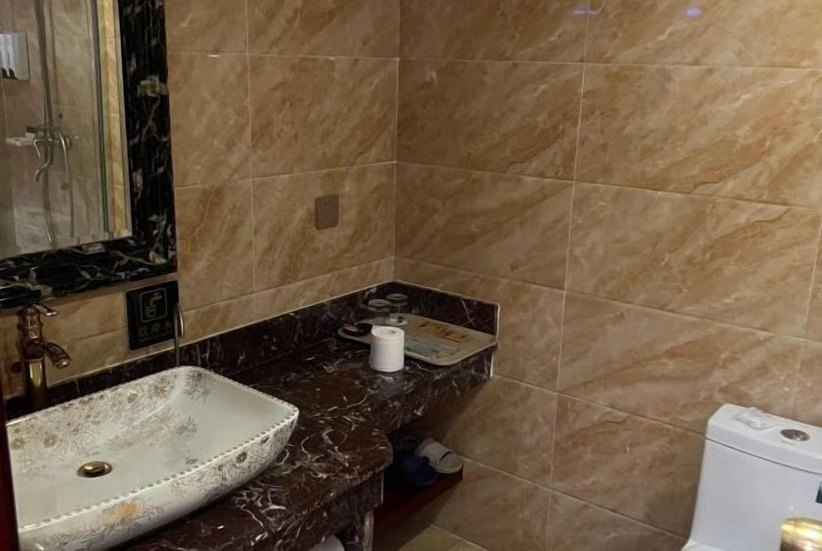Een badkamer met een marmeren wastafel, een spiegel en een toilet.