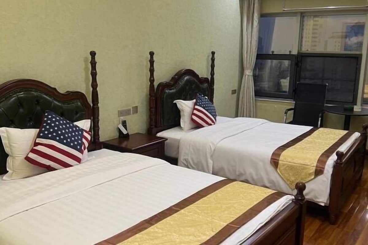 Twee tweepersoonsbedden met houten hoofdborden, wit beddengoed en kussens met de Amerikaanse vlag.