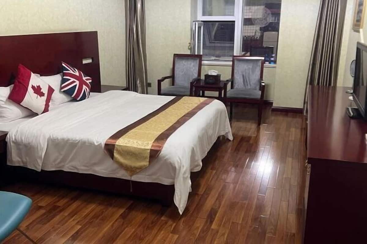 Een hotelkamer met een bed, twee stoelen, een klein tafeltje en een raam.