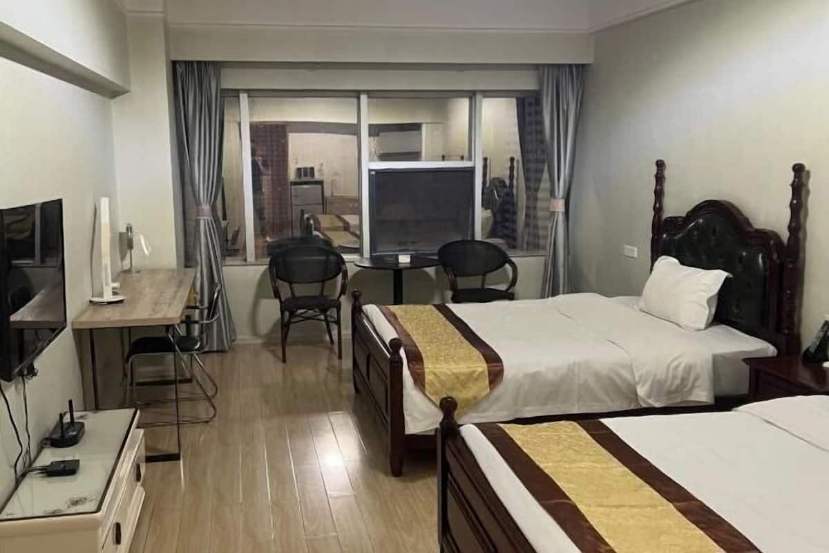 Een hotelkamer met een bed, een bureau, een stoel, een televisie en een raam met gordijnen.