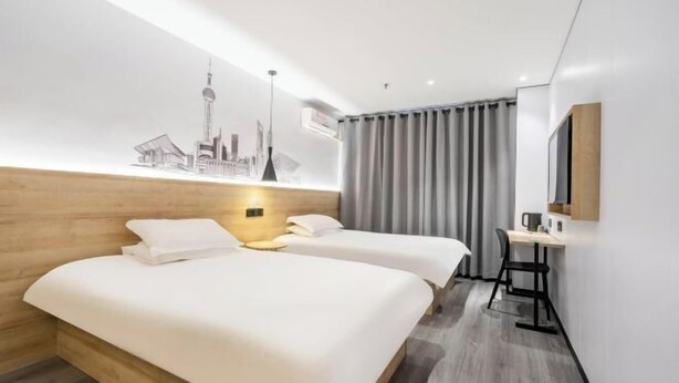 A hotel room with two beds, a desk, a mirror, and a cityscape artwork on the wall. - Changee Hotel MINI (Shanghai Jinshan City Beach) (Shanghai)