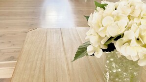 A room with a wooden floor, a white door, a dining table with chairs, and a window with a view of greenery. - Beachside townhouse at Mona Vale beach, spacious and modern , footsteps to beach (Mona Vale)