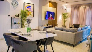 A modern living room with a dining area, a sofa set, and a flat-screen TV.