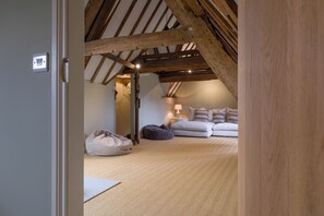 A cozy attic bedroom with exposed wooden beams, a bed, a lamp, and a small rug. - The Mill House Beautiful 4BD Family Home (Stroud)