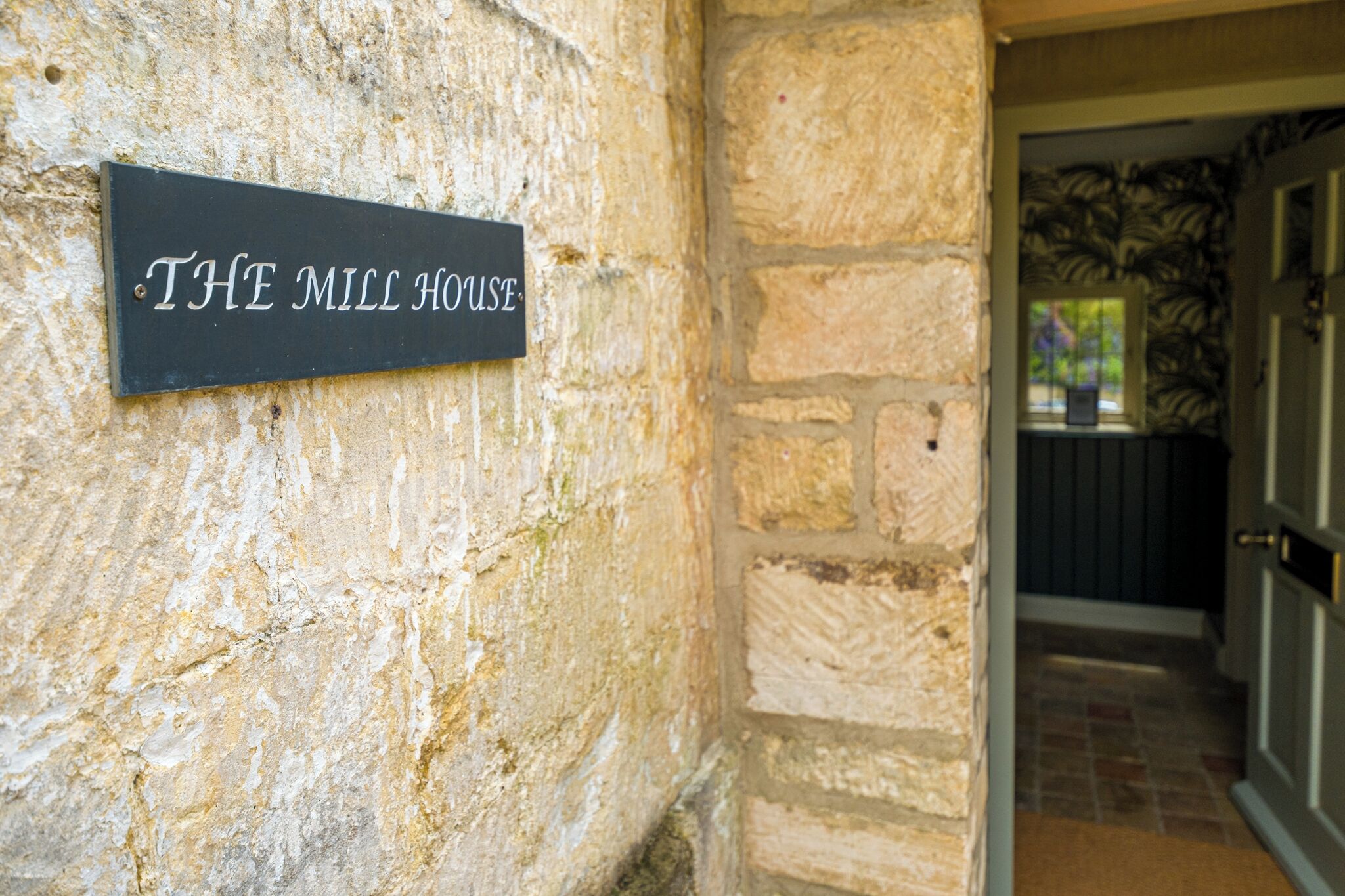 A stone wall with a sign reading "THE MILL HOUSE".