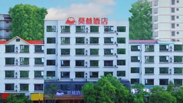 A multi-story hotel with a prominent red sign, air conditioning units, and a clear view of the surrounding buildings.