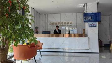 Un mostrador de recepción de hotel con una pantalla digital y una recepcionista.