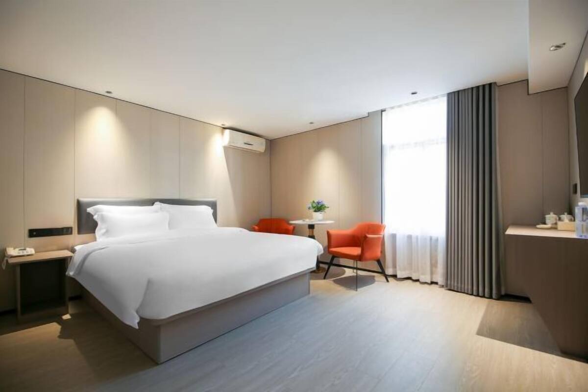 A modern hotel room with a large bed, a desk, and a chair.