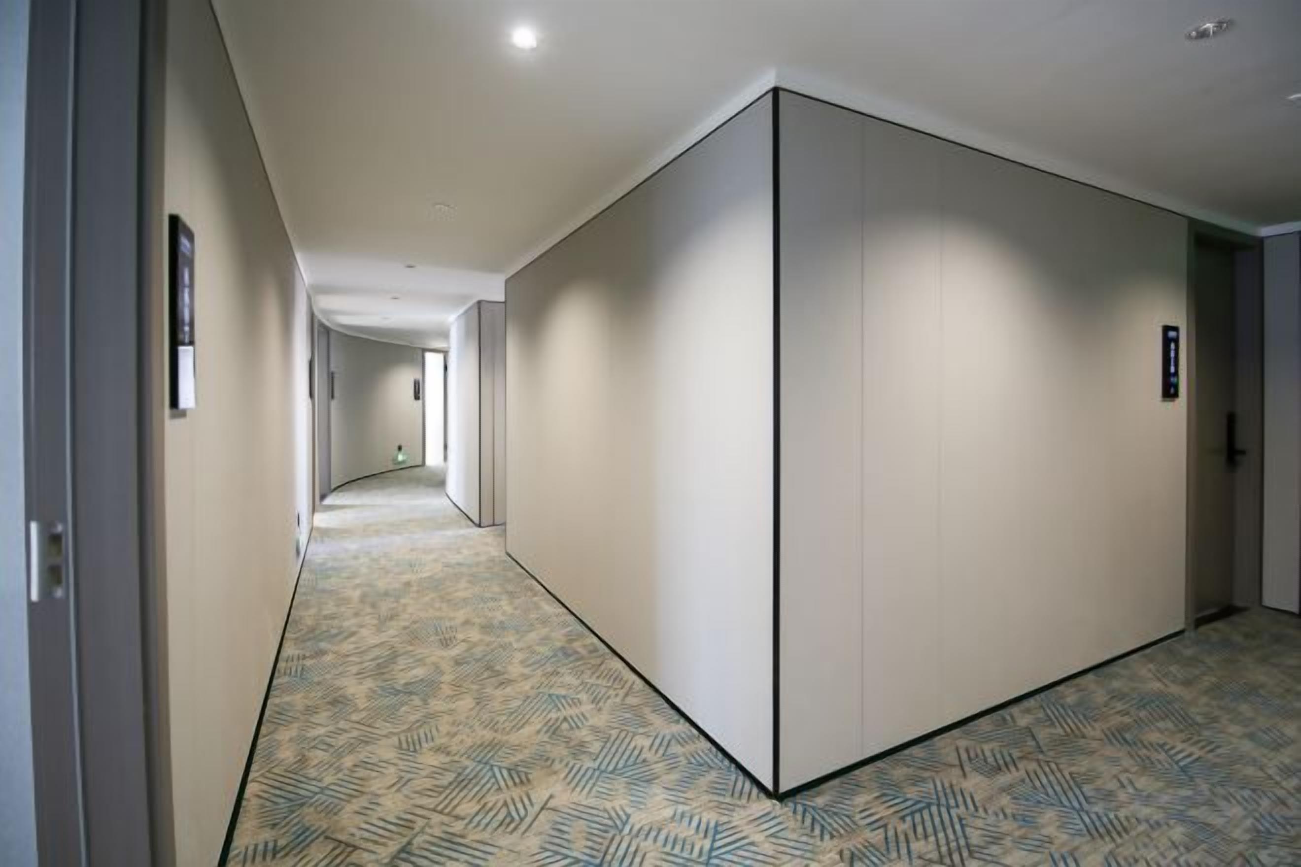 Un pasillo con alfombra estampada, una puerta corredera y una puerta con un letrero.