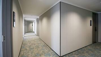 Un pasillo con alfombra estampada, una puerta corredera y una puerta con un letrero.