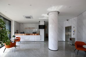 A hotel reception area with a marble reception desk, a large pillar, and seating arrangements. - Zhonghao Shangpin Hotel (Wenzhou Zhuangyuan Branch) (Wenzhou)