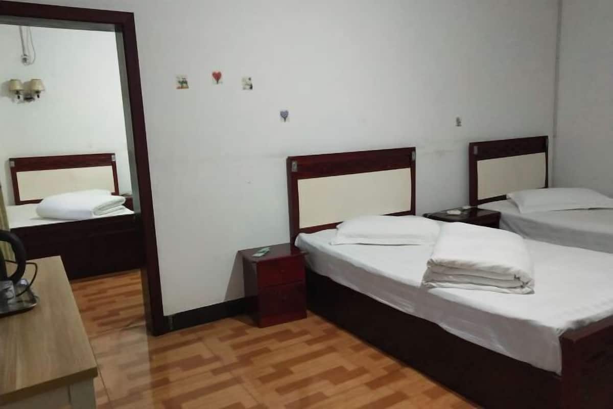 Habitación de hotel con dos camas, un escritorio, una silla, una mesita de noche y un espejo.