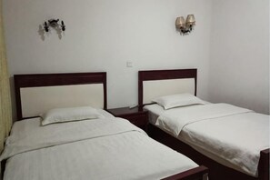Two single beds with wooden headboards, white bedding, and bedside lamps on a white wall. - E'mei Mountain Cuizhu Hotel (Emeishan City)