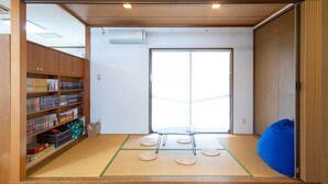 A room with a tatami mat floor, a bookshelf, a sliding door, and a blue bean bag.
