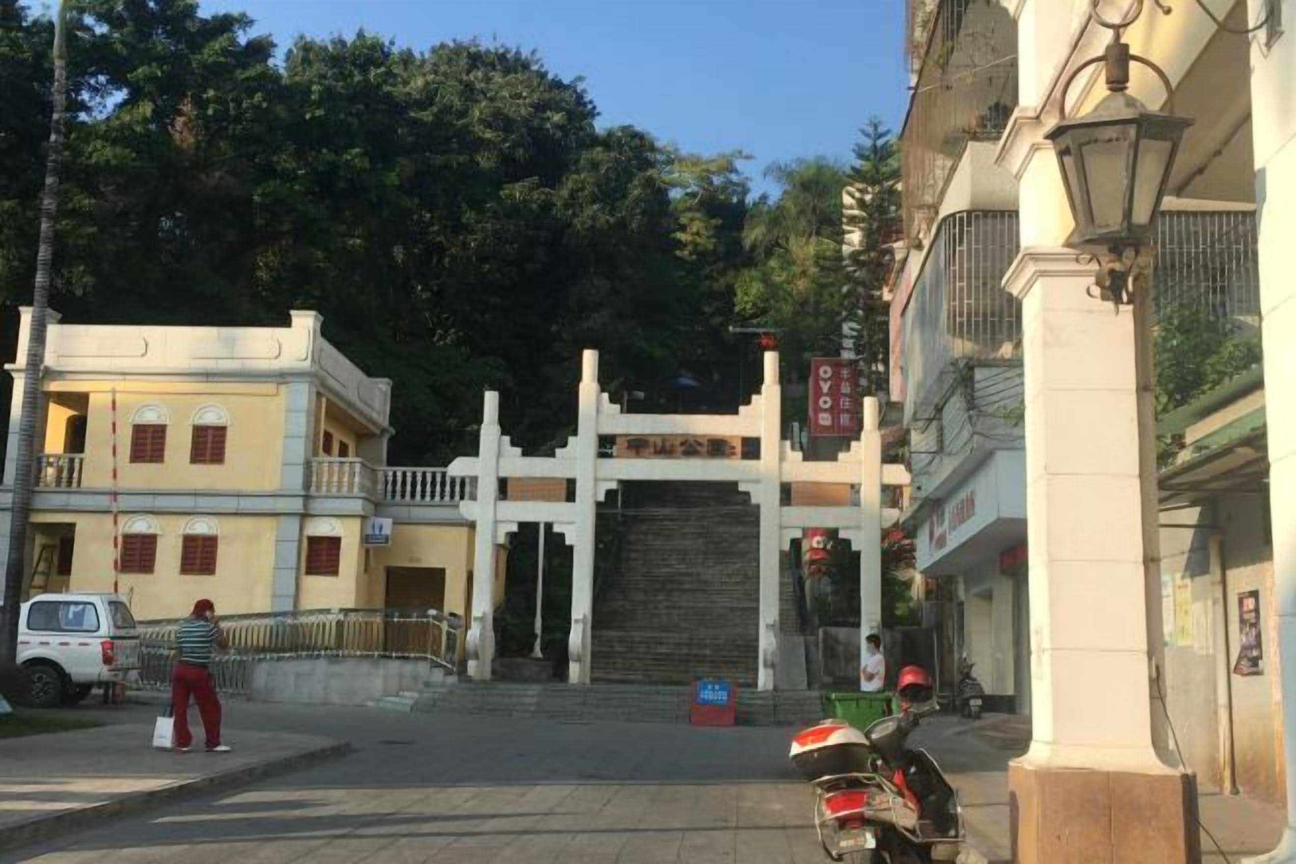 A traditional gate with a sign, a paved entrance, and a parked scooter.