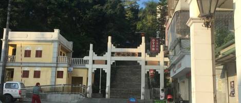 A traditional gate with a sign, a paved entrance, and a parked scooter.