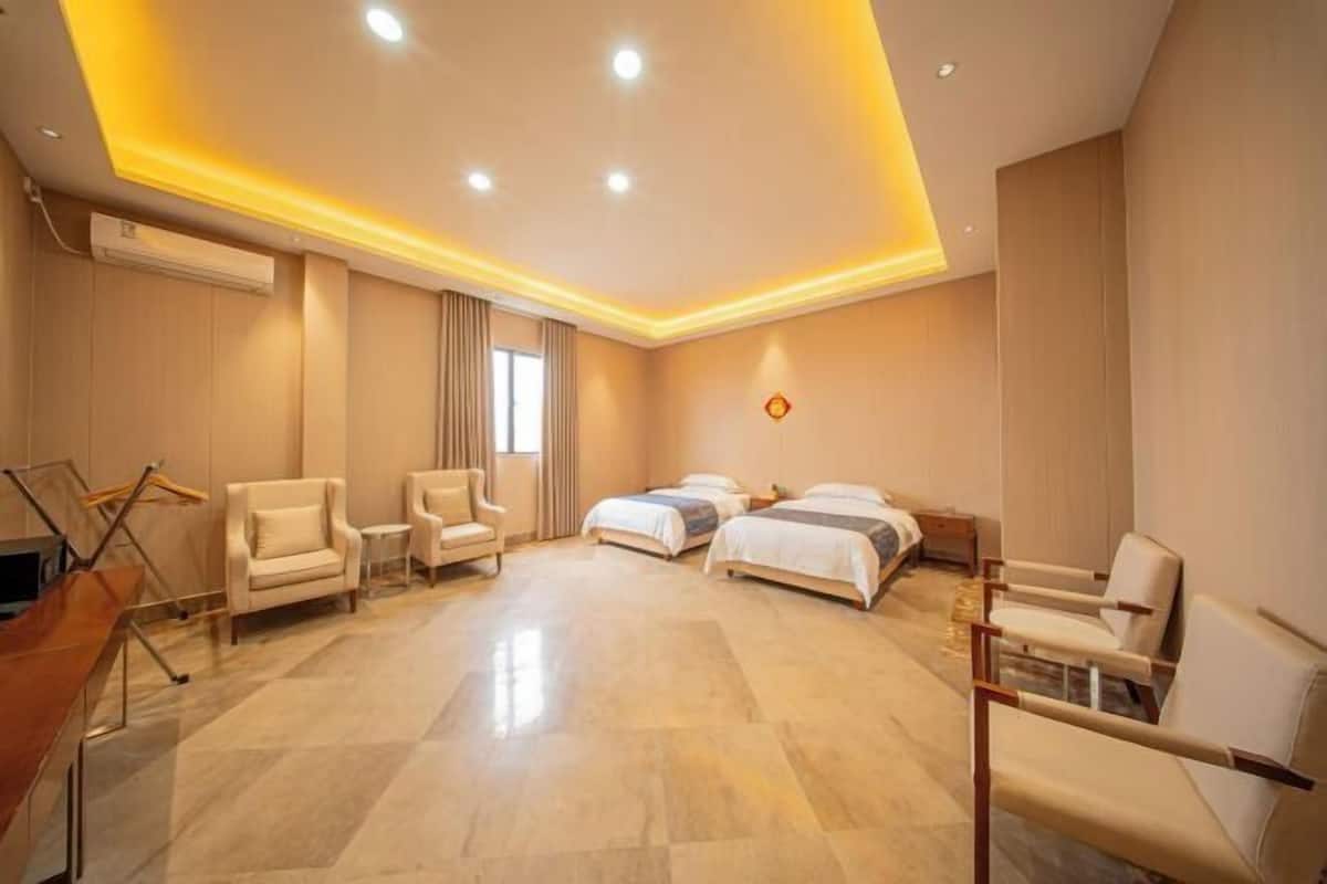 Een hotelkamer met een bed, twee stoelen, een bureau en een raam.
