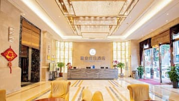A hotel lobby with a reception desk, seating area, and decorative elements.