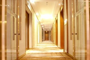 Un pasillo largo y bien iluminado con puertas a ambos lados, que conduce a una zona central.