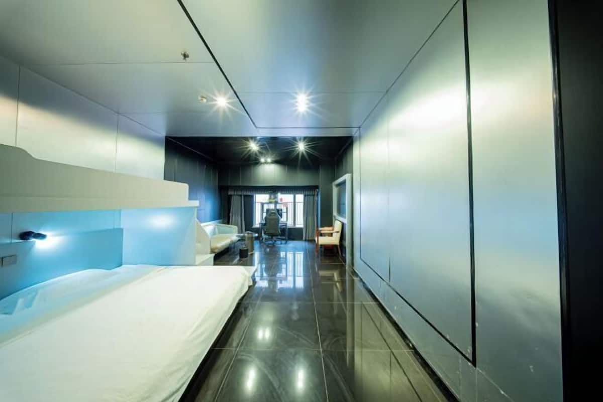 Een moderne hotelkamer met een bed, bureau en stoel.