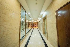A hotel corridor with marble walls, a polished floor, and a wooden door.