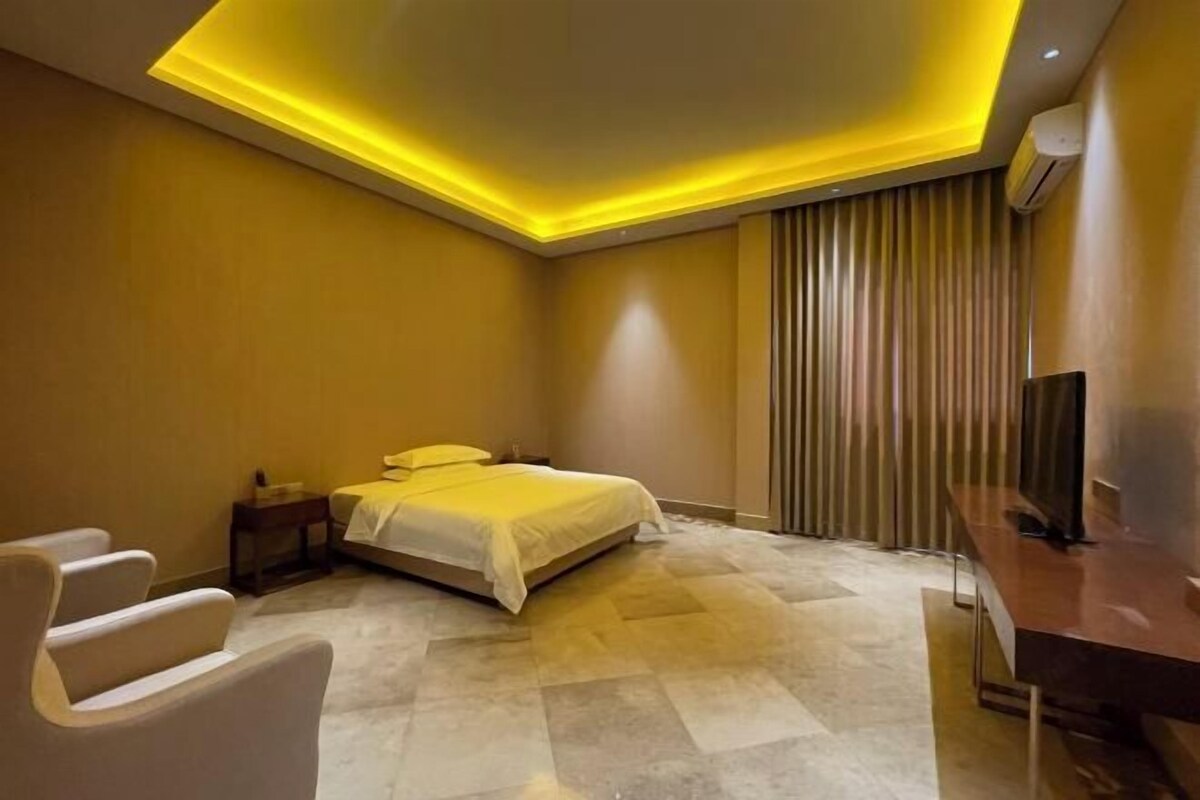 A modern hotel room with a bed, a desk, and a chair.