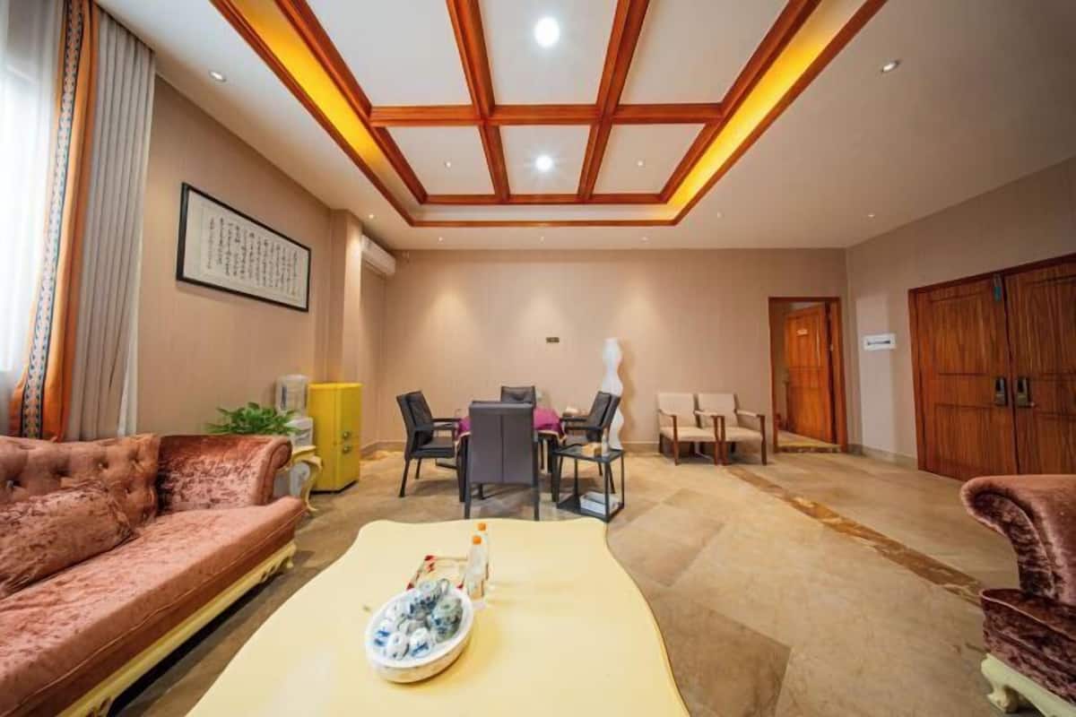 Een hotelkamer met een bank, een eettafel met stoelen, een kast en een grote garderobe.