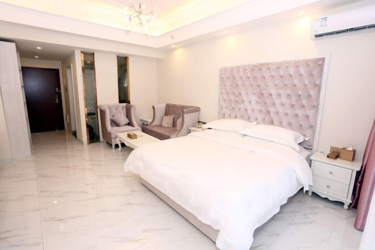 A modern bedroom with a large bed, a nightstand, a chair, and a wardrobe.