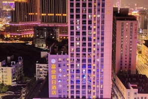 A high-rise building with multiple floors, illuminated windows, and a prominent sign with text.