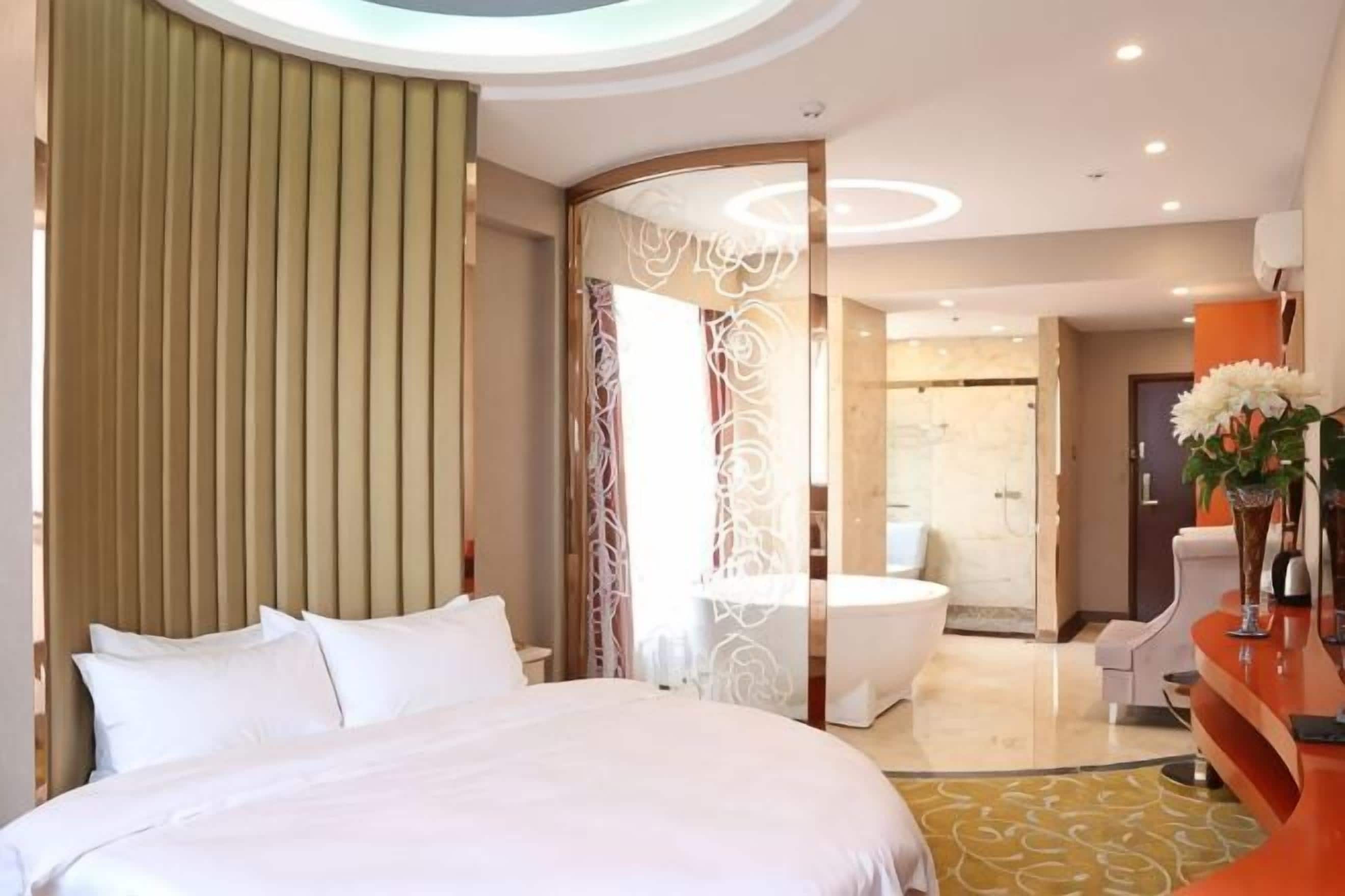 Ein modernes Hotelzimmer mit einem großen Bett, einem Badezimmer mit einer Badewanne und einem Empfangsbereich.