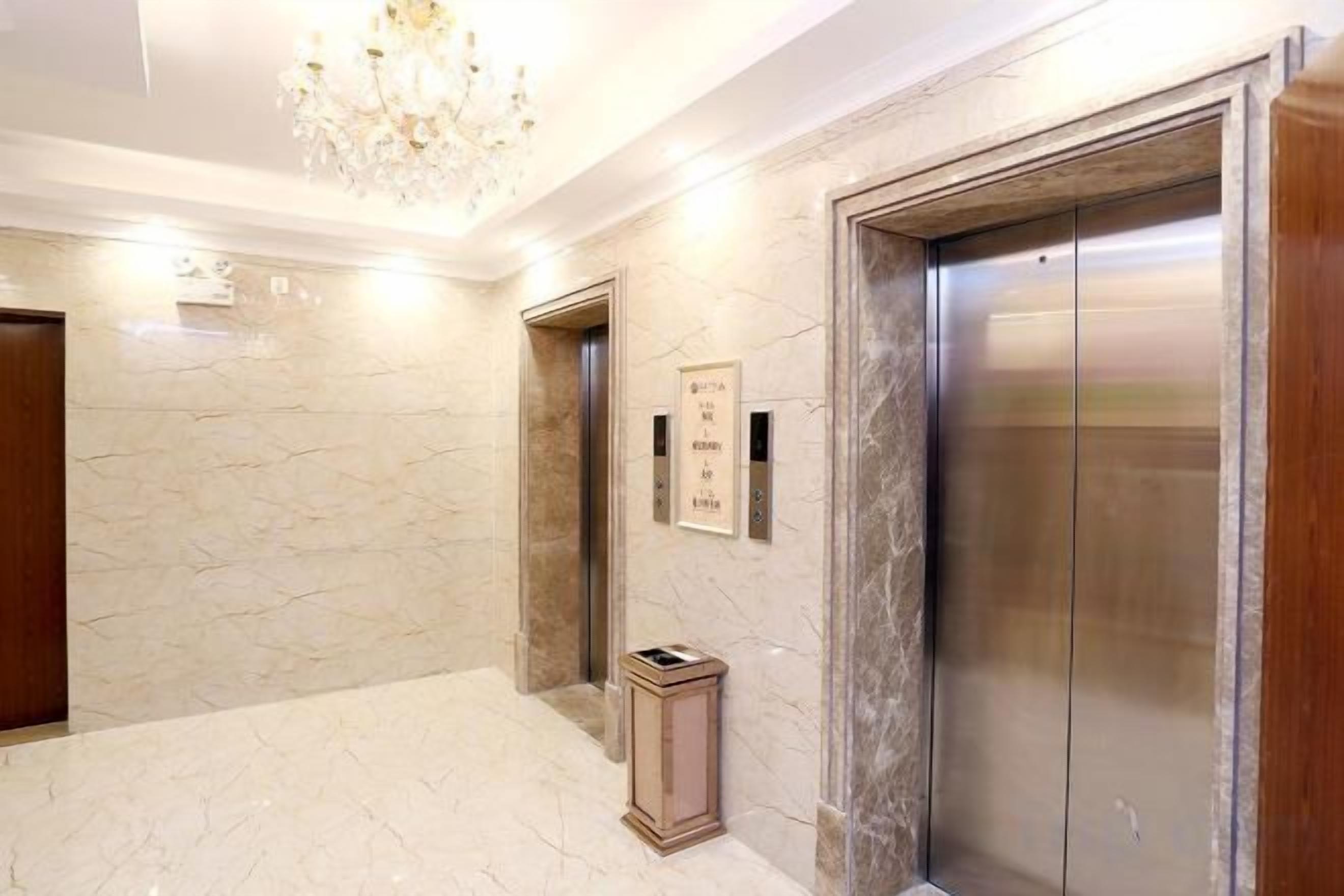 An elevator with a marble wall and a chandelier.