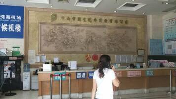 A reception desk with a large wall mural, a blue sign, and a counter with a cash register.