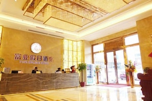 A hotel reception area with a marble counter, a clock, and large windows.