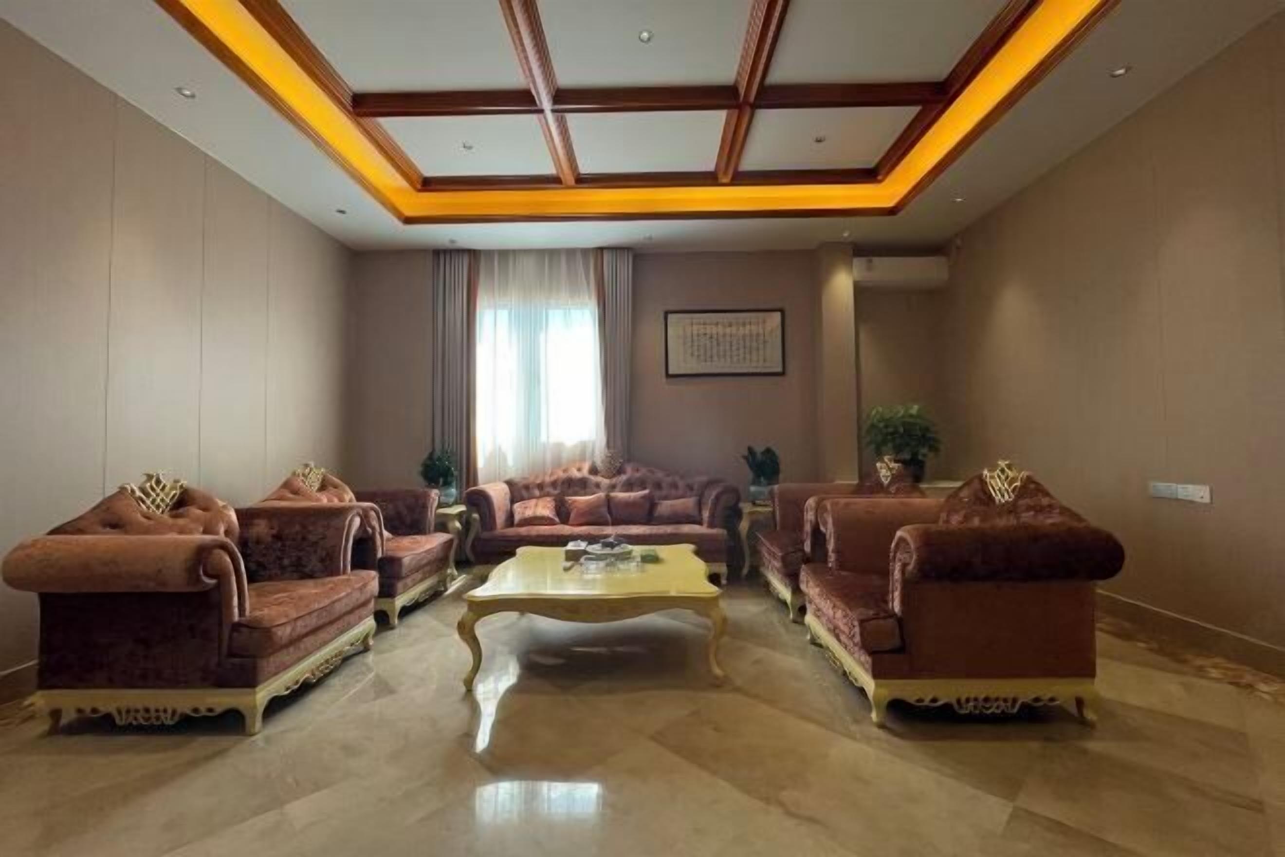 A spacious living room with a high ceiling, a central coffee table, and two sofas with decorative cushions.