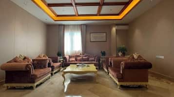 A spacious living room with a high ceiling, a central coffee table, and two sofas with decorative cushions.