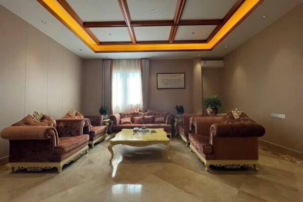 A spacious living room with a high ceiling, a central coffee table, and two sofas with decorative cushions. - Fuyue Holiday Hotel(fuhua street store) (Zhongshan)