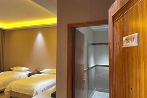 A hotel room with two beds, a wooden door with a room number sign, and a shower area. - Fuyue Holiday Hotel(fuhua street store) (Zhongshan)