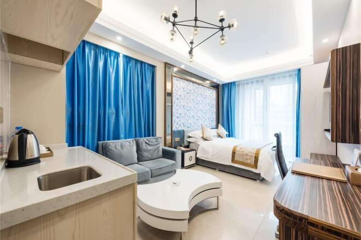 Een moderne hotelkamer met een kitchenette, een bank, een bed en een eethoek.
