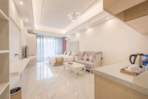 Ein modernes Hotelzimmer mit Bett, Sofa, Couchtisch und einer Küchenzeile.